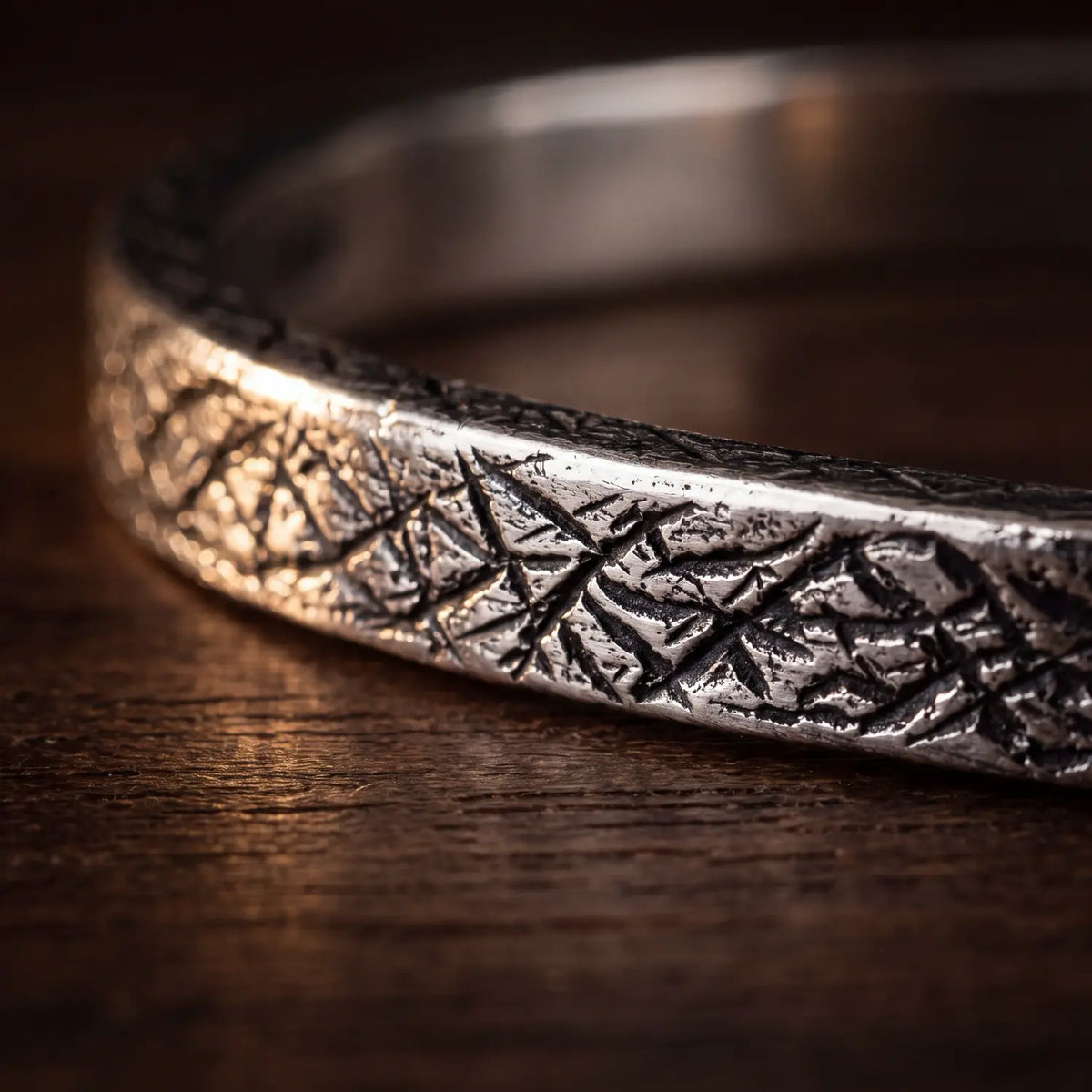 Earth Cuff close-up: handgesneden groeven in massief 925 zilver, licht geoxideerd, op donker hout - PALM. Jewelry